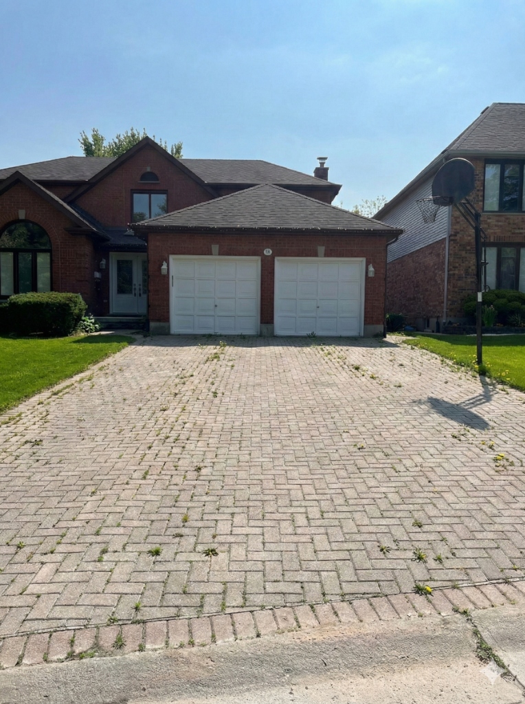 Oil-stained concrete driveway in Oakridge London Ontario before professional pressure washing by Core Exteriors