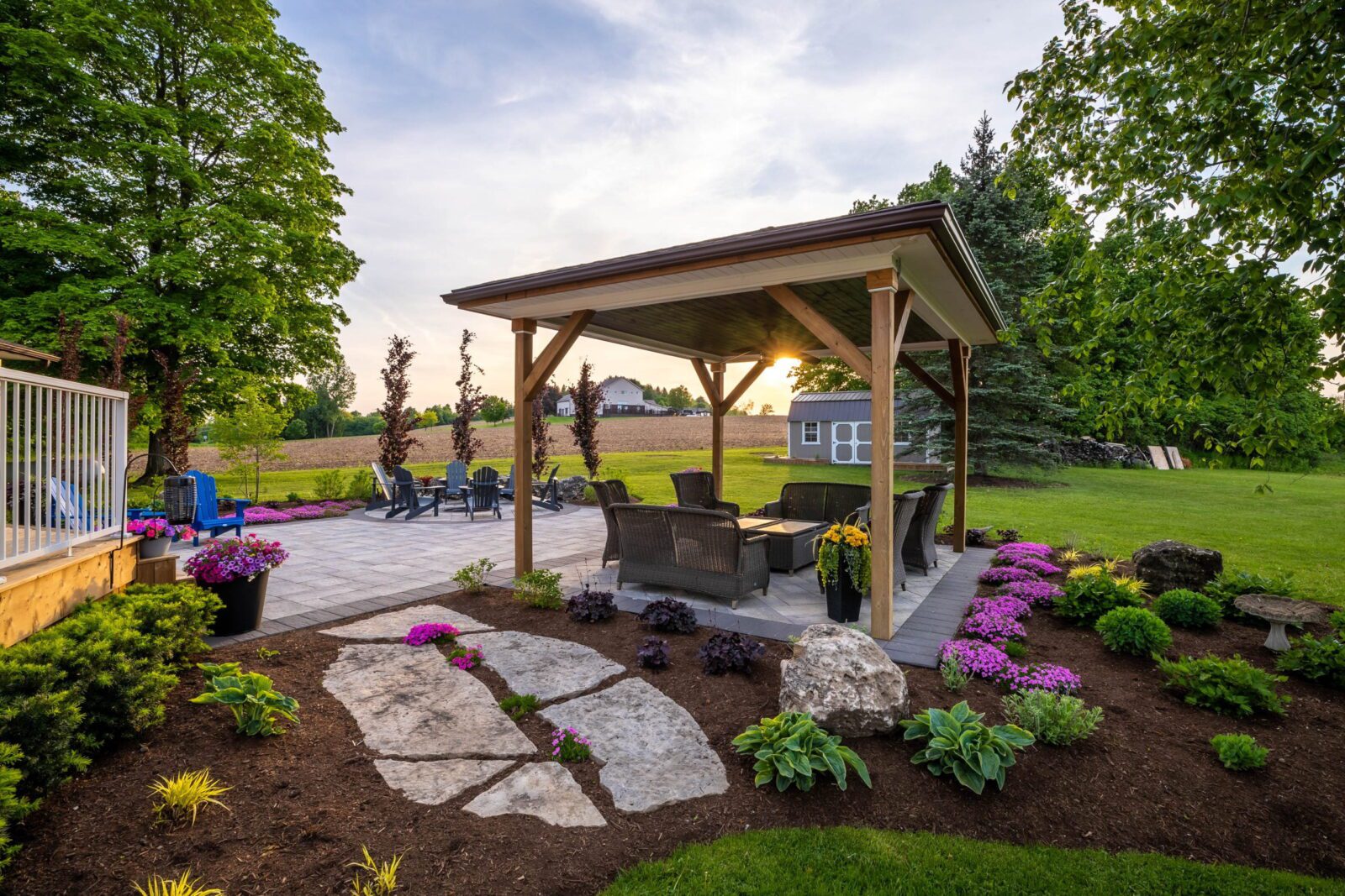 Backyard patio with timber pergola, flagstone path, fire pit and garden beds at a home in Dorchester Ontario