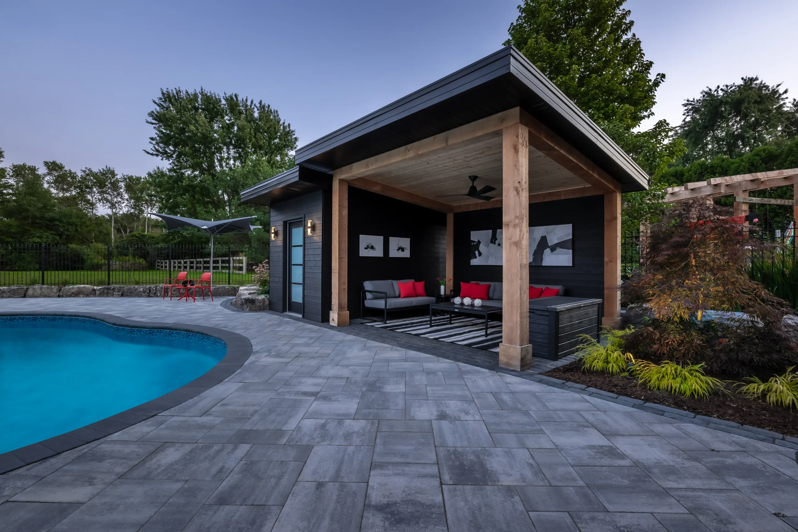 Large format paver pool deck with modern timber cabana and outdoor lounge area in St. Thomas Ontario