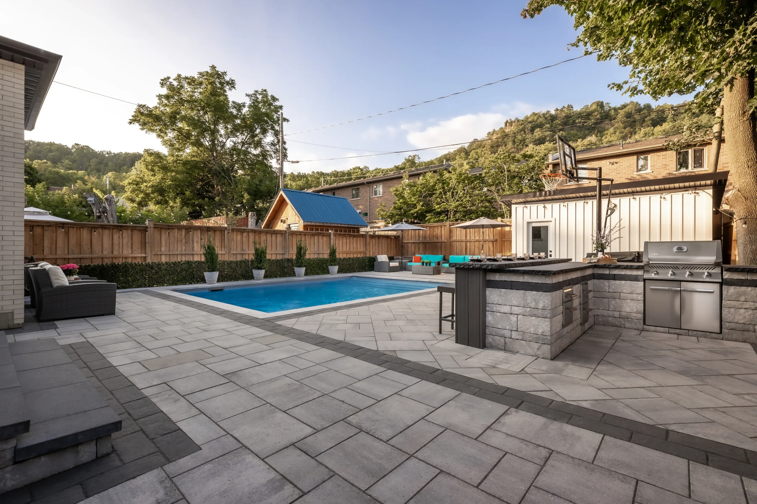 Large paver pool deck with custom outdoor kitchen island and BBQ station in South London Ontario