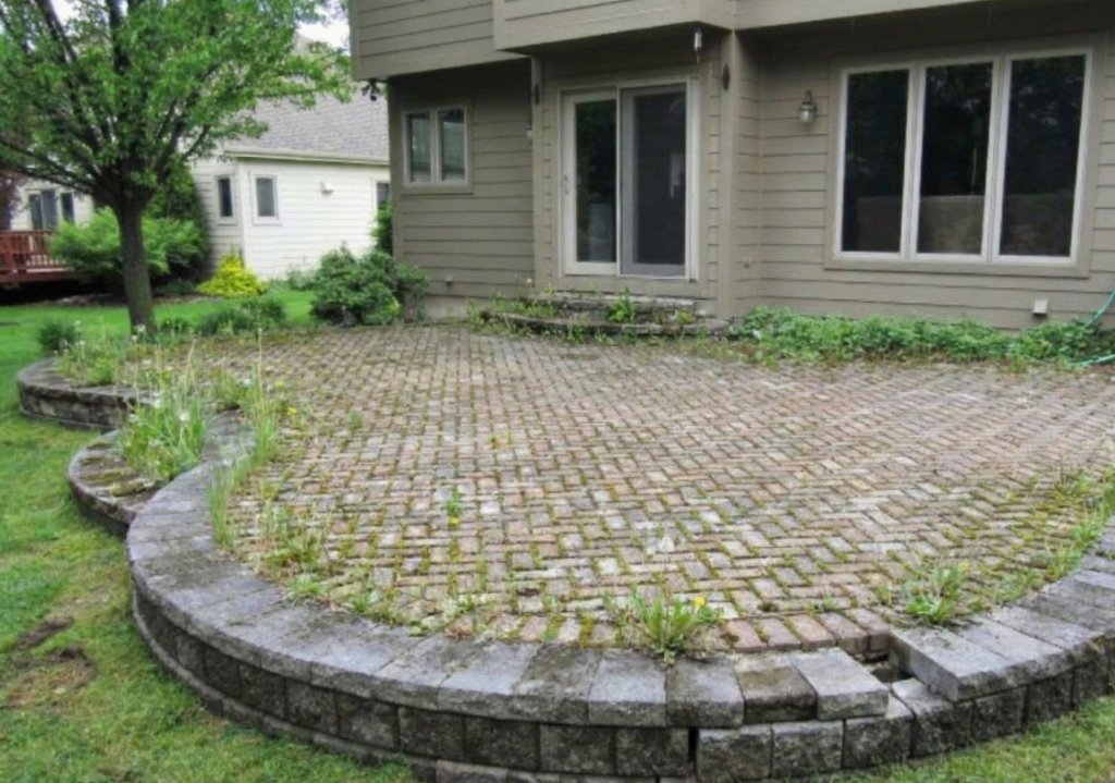 Weed-filled and stained interlock patio in Komoka Ontario before professional cleaning and relevelling by Core Exteriors